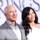 Jeff Bezos stands next to TV personality Lauren Sanchez in front of a poster for Amazon Prime Video's The Lord of the Rings The Rings of Power